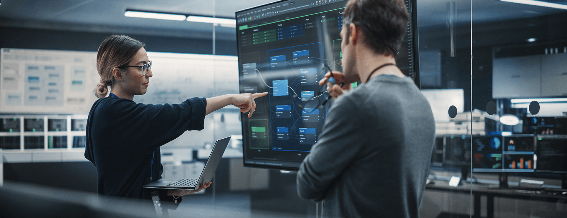 Zwei Personen stehen vor einem Monitor und diskutieren ein Dashboard.